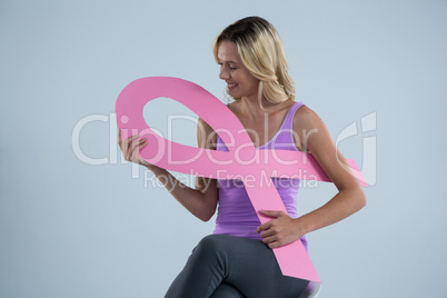 Smiling woman holding Breast Cancer Awareness ribbon