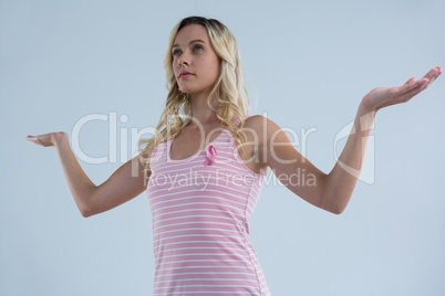 Low angle view of woman with pink ribbon gesturing while looking away