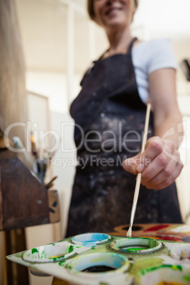 Smiling woman painting on canvas