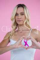 Breast Cancer Awareness ribbon seen through heart shape made by smiling woman