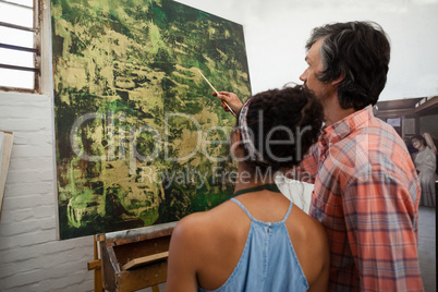 Man assisting woman in painting