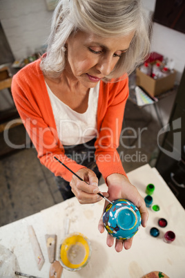 Senior woman painting bowl in drawing class