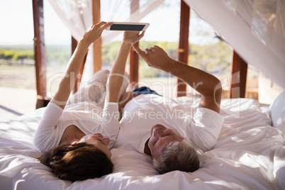 Happy couple using digital tablet on bed