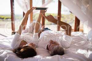 Happy couple using digital tablet on bed