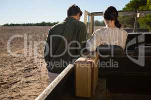 Rear view of man by woman sitting in off road vehicle