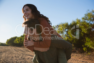 Man giving woman piggyback ride on field