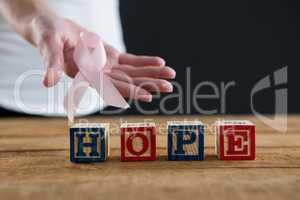 Mid section of woman showing Breast Cancer Awareness ribbon with hope text on table