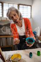 Senior woman painting bowl in drawing class