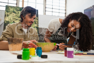 Man assisting woman in painting bowl