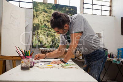 Attentive man painting at table