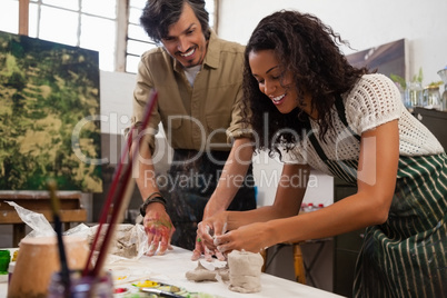 Man assisting woman in molding clay