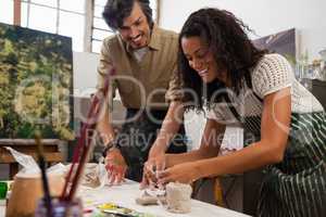 Man assisting woman in molding clay