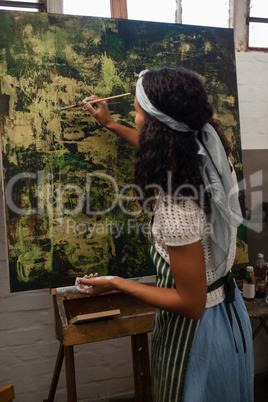 Attentive woman painting on canvas
