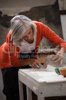 Attentive senior woman shaping a molded clay