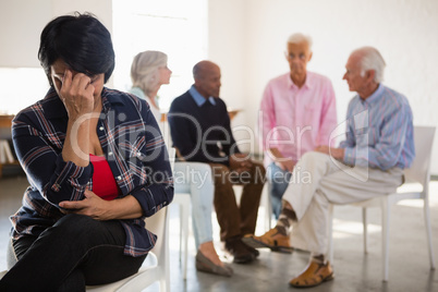 Worried senior woman with friends in background