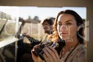 Thoughtful woman sitting with binoculars in vehicle