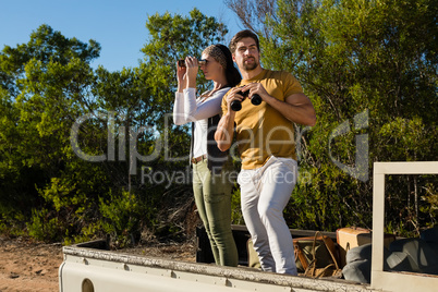 Couple looking through binoculars in off road vehicle