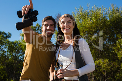 Happy couple with binoculars at forest