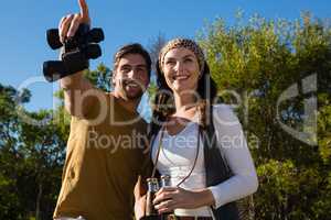 Happy couple with binoculars at forest