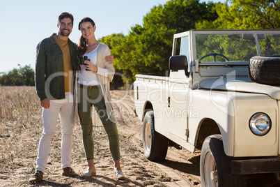 Portrait of couple by off road vehicle at forest