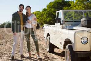 Portrait of couple by off road vehicle at forest