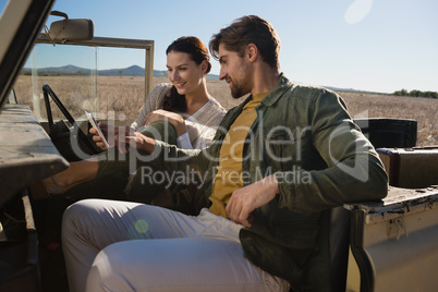 Couple using phone in off road vehicle
