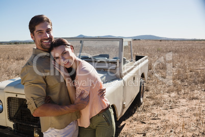 Portrait of happy couple by off road vehicle