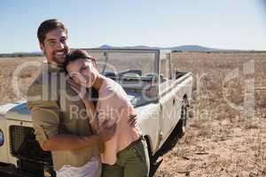 Portrait of happy couple by off road vehicle
