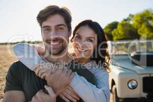 Portrait of smiling couple by vehicle