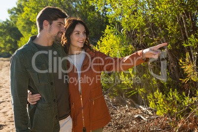 Woman with man pointing by trees