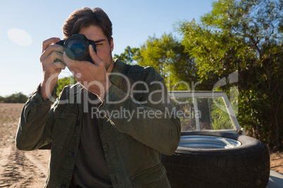 Young man photographing by vehicle