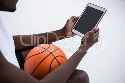 Player holding basketball while using digital tablet