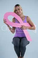 Portrait of smiling woman holding Breast Cancer Awareness ribbon