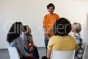 Man standing by fiends sitting on chair