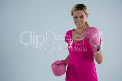 Portrait of smiling woman with boxing gloves and and pink ribbon