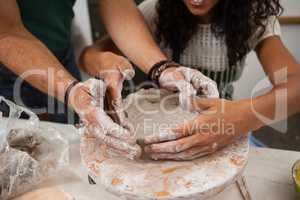 Man assisting woman in pottery