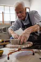 Attentive senior man molding clay