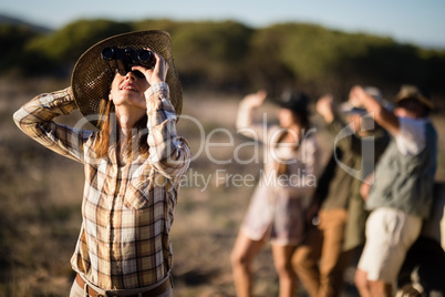 Beautiful woman looking through binoculars during safari vacation