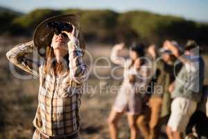 Beautiful woman looking through binoculars during safari vacation