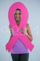 Portrait of young female with cardboard Breast Cancer Awareness ribbon
