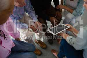 High angle view of woman showing tablet to senior adults