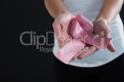 Mid section of woman holding pink ribbon