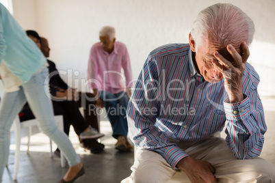 Tensed senior man with friends in background