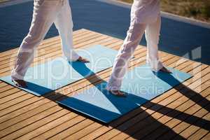 Low section of couple practicing yoga on at poolside