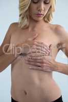 Young woman touching breast while examining lumps