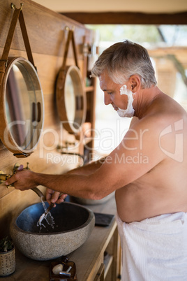 Man washing razor in cottage
