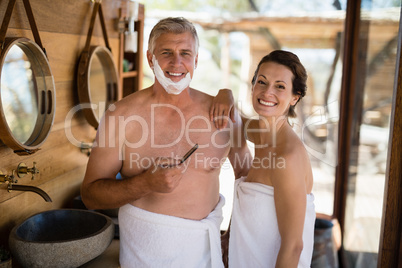 Portrait of couple smiling while shaving in cottage