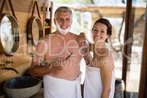 Portrait of couple smiling while shaving in cottage