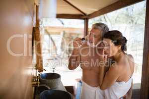 Couple standing with arm around while shaving in cottage