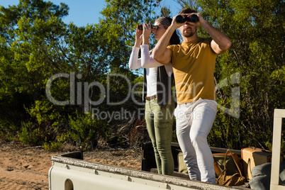 Couple looking through binoculars at forest